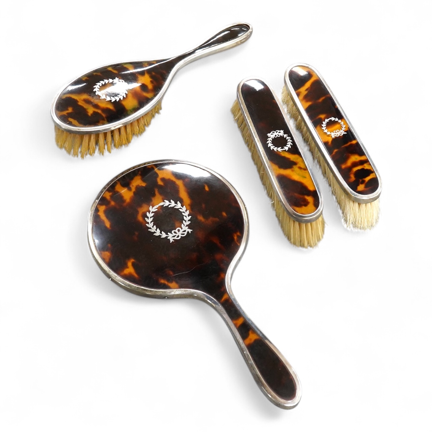 A matched George V silver and tortoiseshell mounted four piece mirror and brush set, Birmingham, 1927/8/9, mirror 22.7cm.
